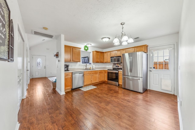 kitchen with a sink, an inviting chandelier, stainless steel appliances, light countertops, and dark wood finished floors