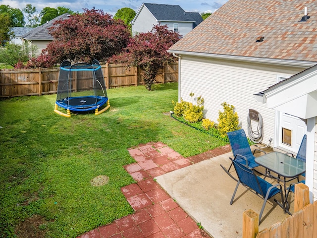 view of yard with a trampoline, a fenced backyard, and a patio area