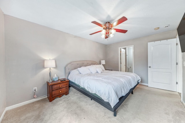 bedroom featuring light colored carpet, ceiling fan, ensuite bathroom, and baseboards