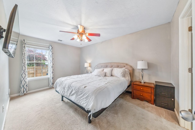 bedroom with light colored carpet, visible vents, a ceiling fan, and baseboards