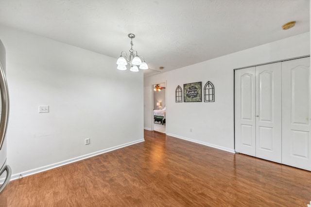 interior space featuring wood finished floors, a chandelier, and baseboards