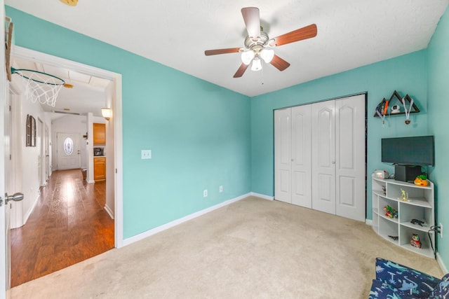 unfurnished bedroom featuring carpet floors, a closet, attic access, baseboards, and a ceiling fan