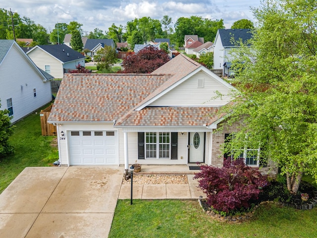 view of front facade with a porch, a front yard, a residential view, concrete driveway, and an attached garage