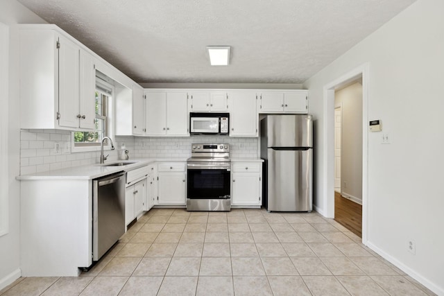 kitchen with light countertops, stainless steel appliances, a sink, and tasteful backsplash