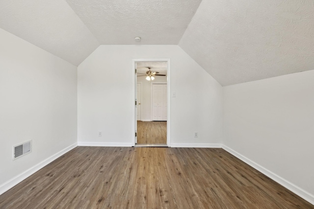 bonus room with visible vents, lofted ceiling, wood finished floors, baseboards, and a textured ceiling