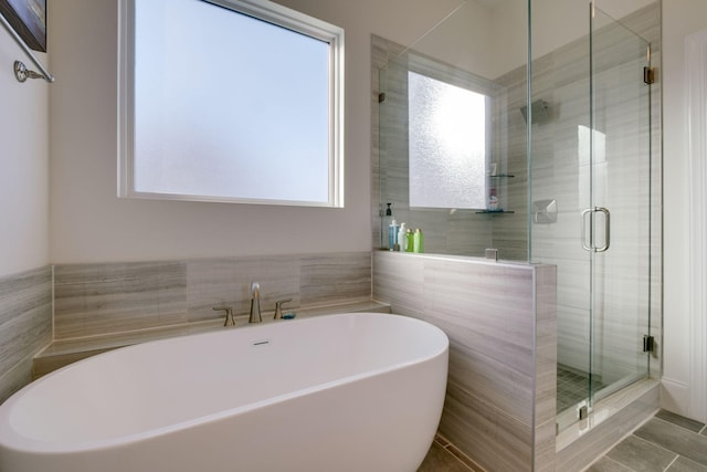 full bath featuring a stall shower, a freestanding bath, tile patterned floors, and a healthy amount of sunlight