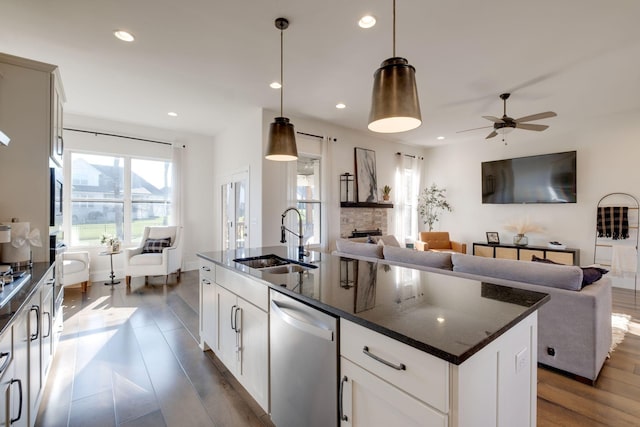 kitchen featuring stainless steel appliances, ceiling fan, open floor plan, and a sink