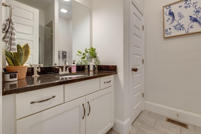 bathroom featuring tiled shower, tile patterned floors, vanity, baseboards, and visible vents