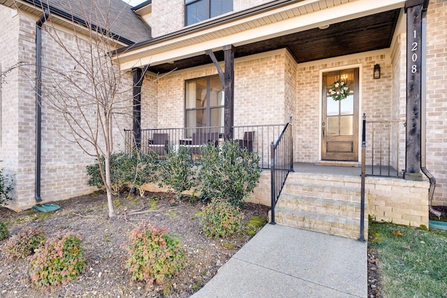view of exterior entry with covered porch and brick siding