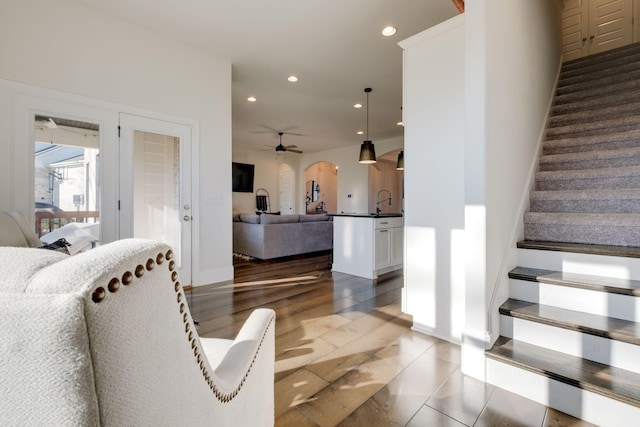 stairway with ceiling fan, baseboards, arched walkways, recessed lighting, and wood finished floors