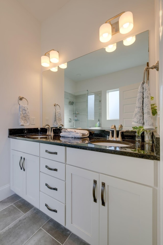 bathroom with tile patterned floors, a tile shower, double vanity, and a sink