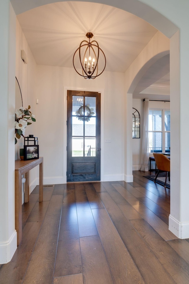 foyer featuring an inviting chandelier, a healthy amount of sunlight, hardwood / wood-style floors, and arched walkways