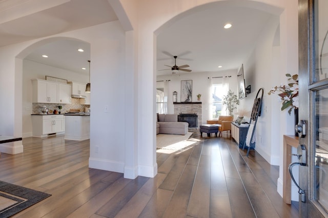 entrance foyer featuring a fireplace, ceiling fan, baseboards, and dark wood finished floors