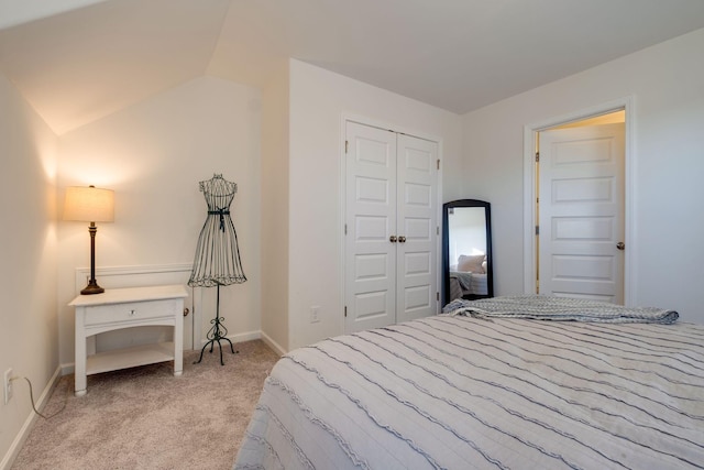 bedroom with a closet, light colored carpet, and baseboards
