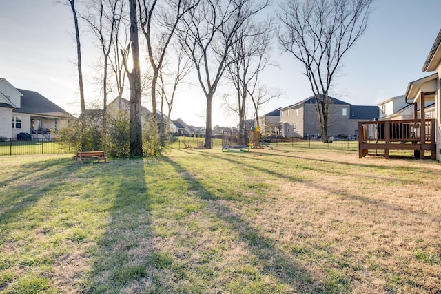 view of yard featuring a residential view, a deck, a trampoline, and a fenced backyard