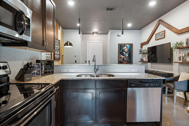 kitchen featuring light stone counters, a sink, appliances with stainless steel finishes, visible vents, and backsplash