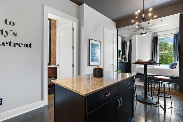 kitchen featuring a notable chandelier, a center island, baseboards, finished concrete floors, and dark cabinets