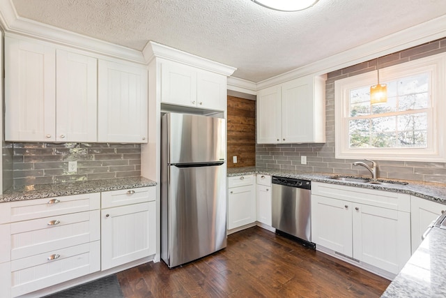kitchen featuring tasteful backsplash, appliances with stainless steel finishes, white cabinets, a sink, and dark wood-type flooring