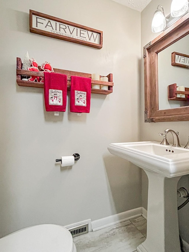 bathroom with visible vents, toilet, and baseboards