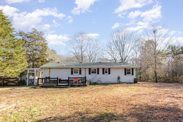 back of property with a wooden deck, a yard, fence, and brick siding