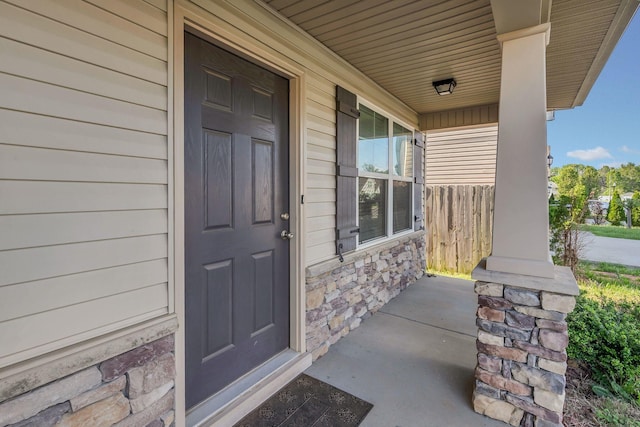 property entrance with a porch and stone siding