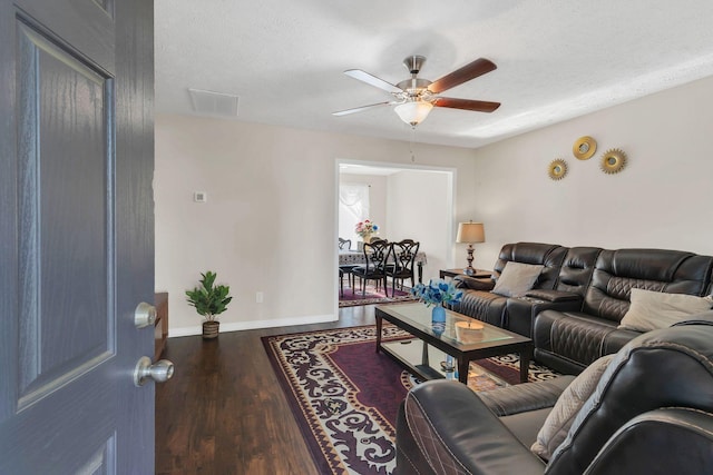 living room with a textured ceiling, a ceiling fan, baseboards, wood finished floors, and visible vents