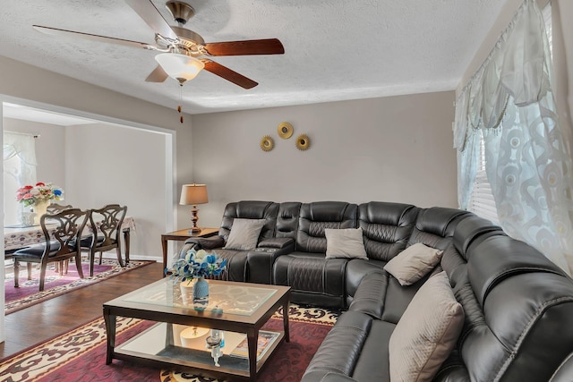 living area with ceiling fan, dark wood finished floors, and a textured ceiling
