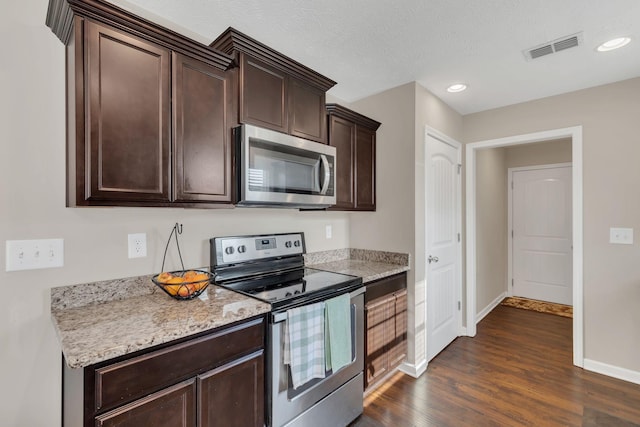 kitchen featuring visible vents, dark brown cabinetry, baseboards, dark wood finished floors, and stainless steel appliances