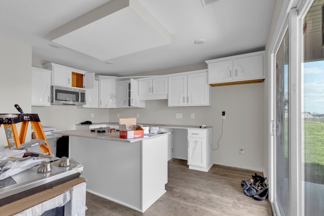 215 Donegal Dr, Clarksville, TN 37042 - kitchen with white cabinetry, a center island, wood finished floors, and stainless steel microwave