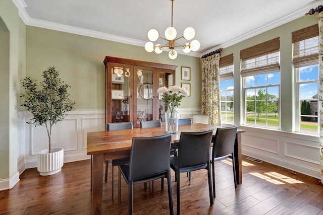 dining area featuring a decorative wall, crown molding, and a notable chandelier