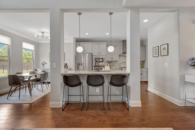 kitchen featuring a sink, stainless steel appliances, a kitchen bar, dark wood-type flooring, and baseboards