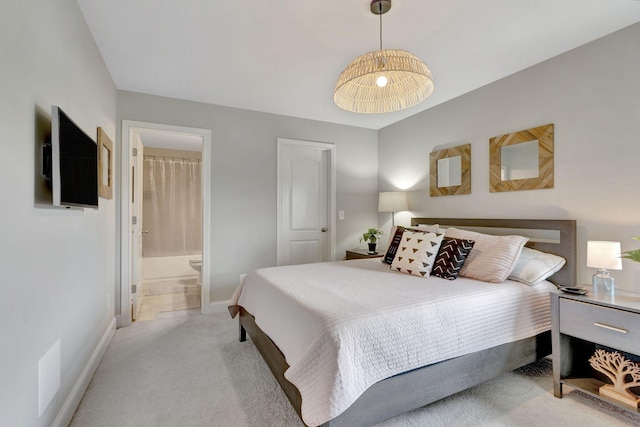 bedroom featuring baseboards, ensuite bath, and light colored carpet