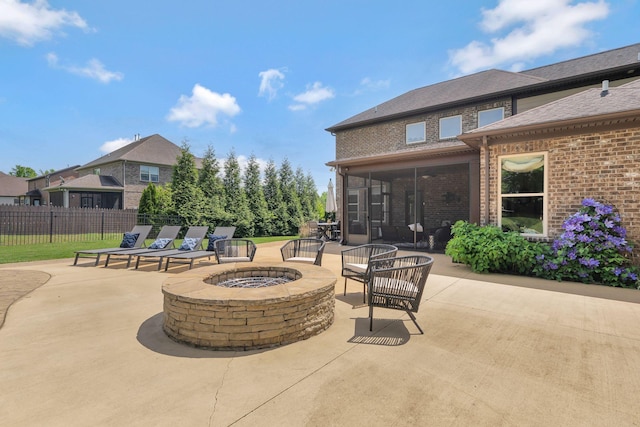 view of patio / terrace featuring a fire pit, fence, and a sunroom