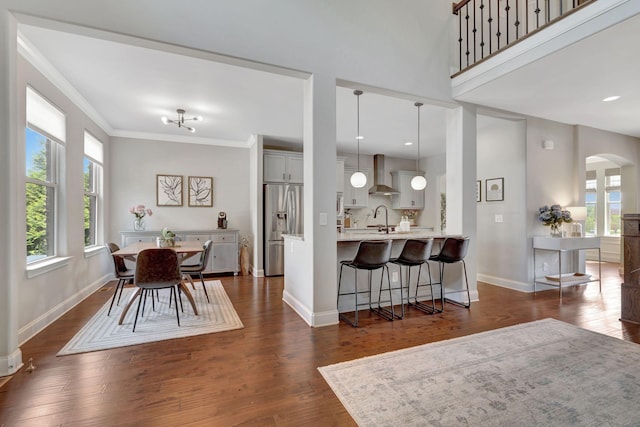 dining area featuring baseboards, arched walkways, and dark wood-type flooring