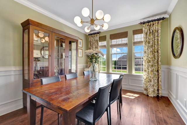 dining space featuring an inviting chandelier, a decorative wall, wainscoting, crown molding, and dark wood-type flooring