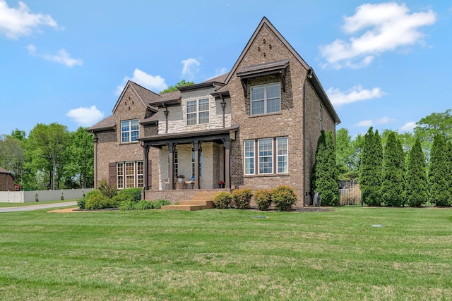 view of front of property featuring fence, a front lawn, brick siding, and stone siding