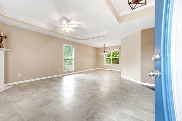 spare room with crown molding, ceiling fan with notable chandelier, baseboards, and a tray ceiling