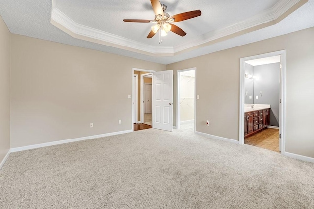 unfurnished bedroom featuring a raised ceiling, baseboards, carpet floors, ornamental molding, and a spacious closet