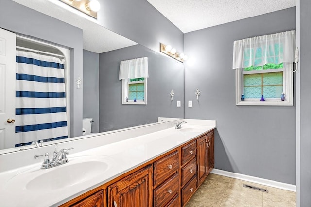 bathroom with double vanity, visible vents, baseboards, and a sink