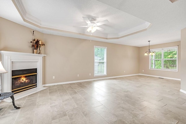 unfurnished living room featuring a textured ceiling, crown molding, a tray ceiling, and ceiling fan with notable chandelier