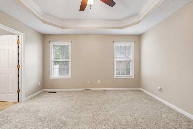 carpeted spare room with visible vents, crown molding, a tray ceiling, and a ceiling fan