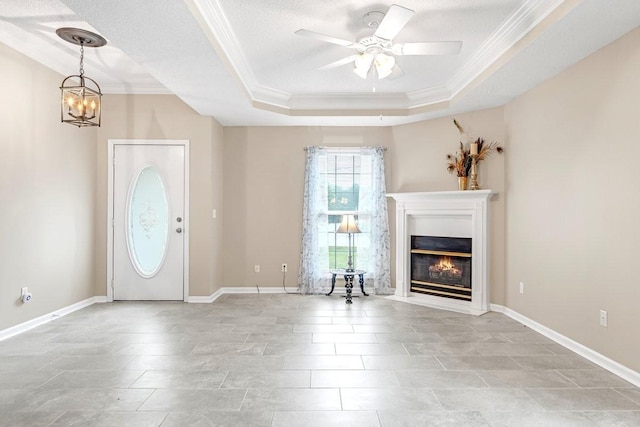 entrance foyer with a fireplace with flush hearth, a raised ceiling, crown molding, and ceiling fan with notable chandelier