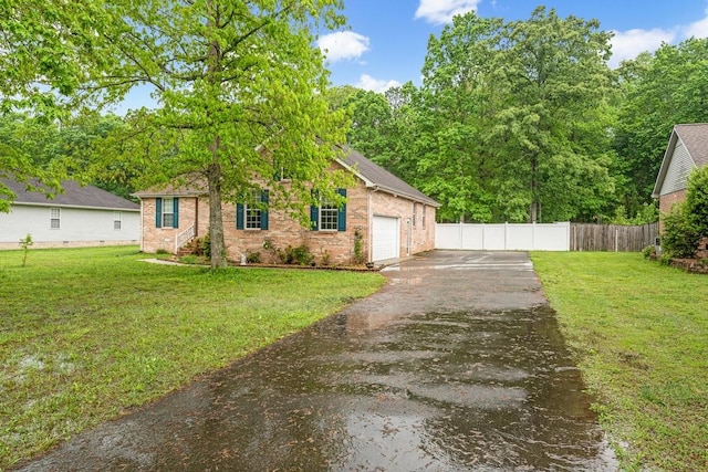 view of front facade with a front lawn, fence, an attached garage, and aphalt driveway