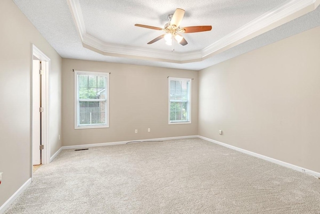 unfurnished room featuring light colored carpet, a textured ceiling, crown molding, and a tray ceiling