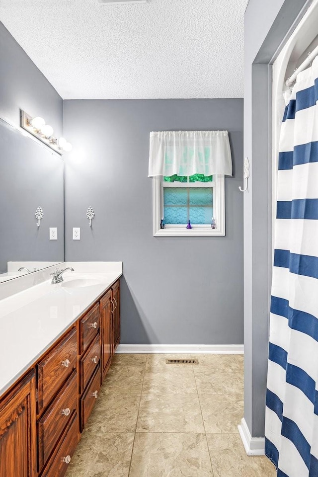 full bathroom with tile patterned flooring, vanity, baseboards, visible vents, and a textured ceiling
