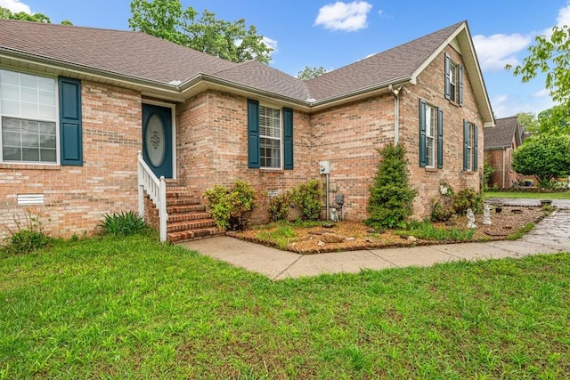 view of front facade featuring roof with shingles, brick siding, and a front lawn