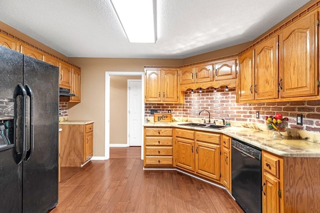 kitchen featuring a sink, light countertops, baseboards, black appliances, and dark wood-type flooring