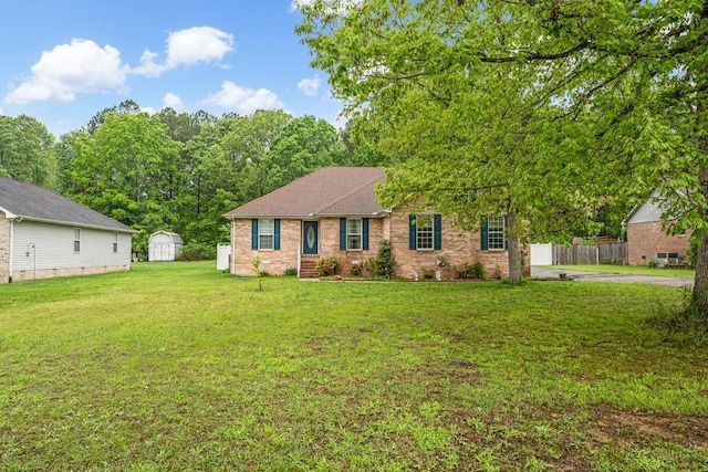 ranch-style house featuring an outdoor structure, a shed, a front yard, fence, and brick siding