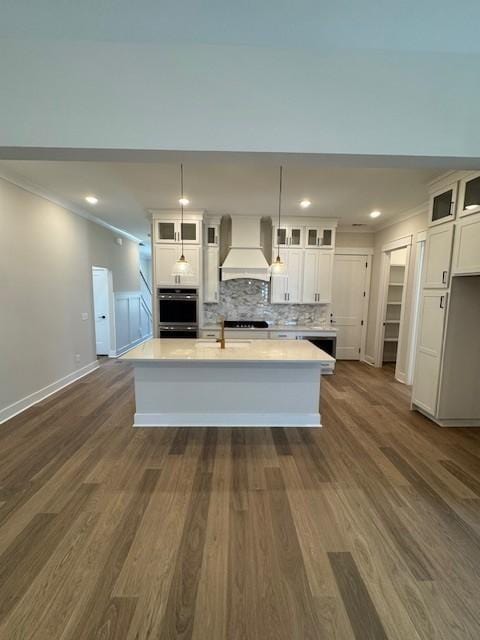 5738 Lennis Ln, Murfreesboro, TN 37129 - kitchen featuring custom exhaust hood, white cabinets, light countertops, ornamental molding, and a center island with sink