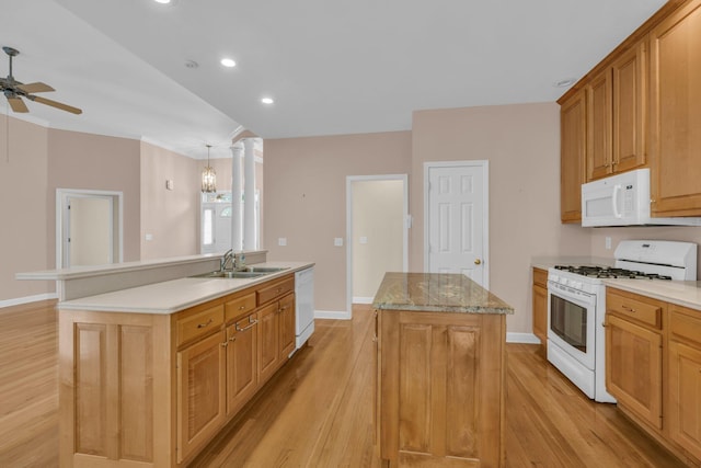 kitchen with a sink, light wood-style floors, an island with sink, and white appliances